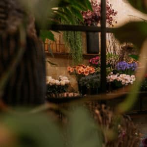 Vibrant étalage de fleurs fraîches dans une boutique, avec roses crème, gerberas oranges et iris bleus, encadré par du feuillage.